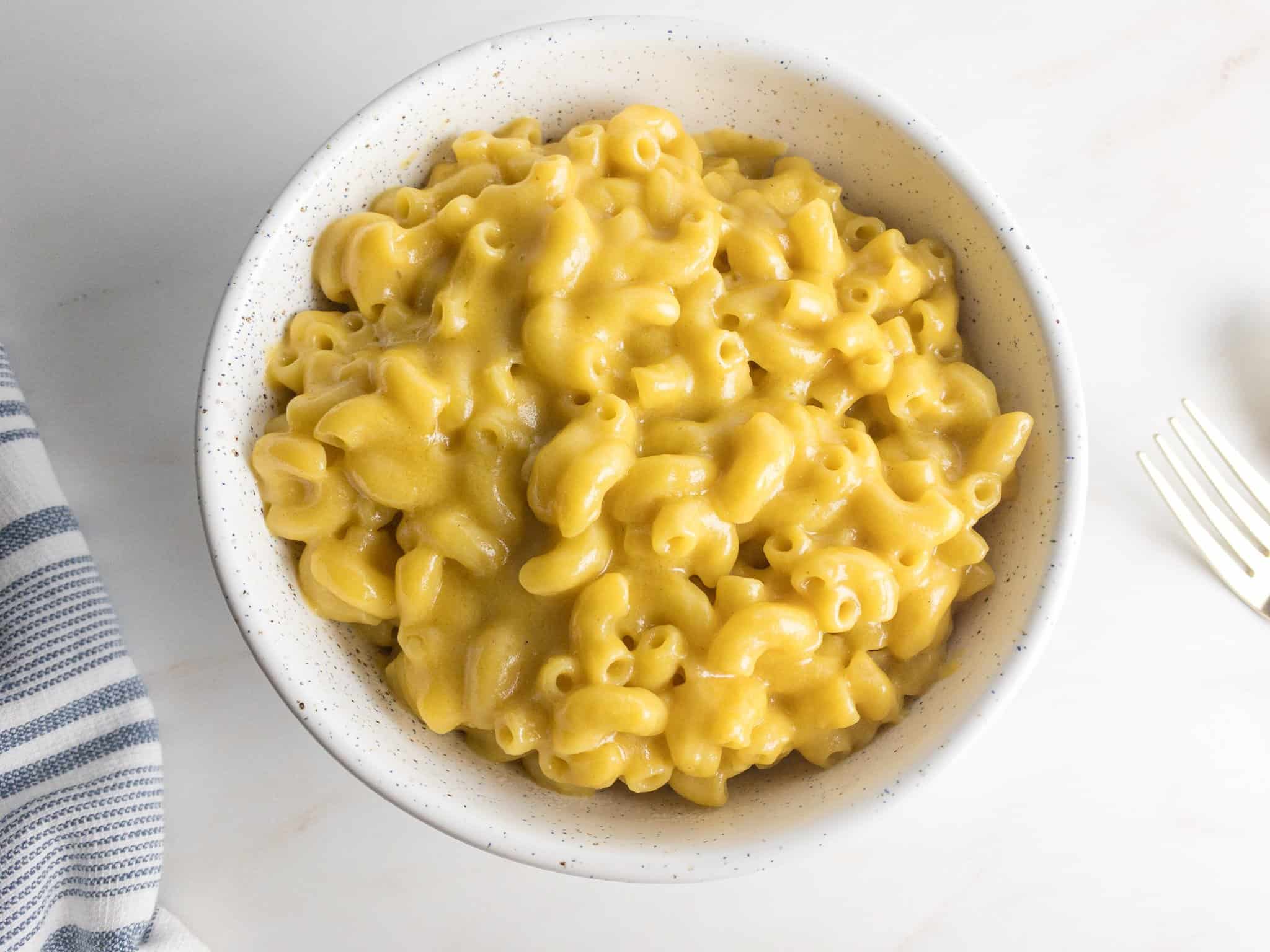 Overhead shot of dairy-free Mac and cheese in a white speckled bowl.