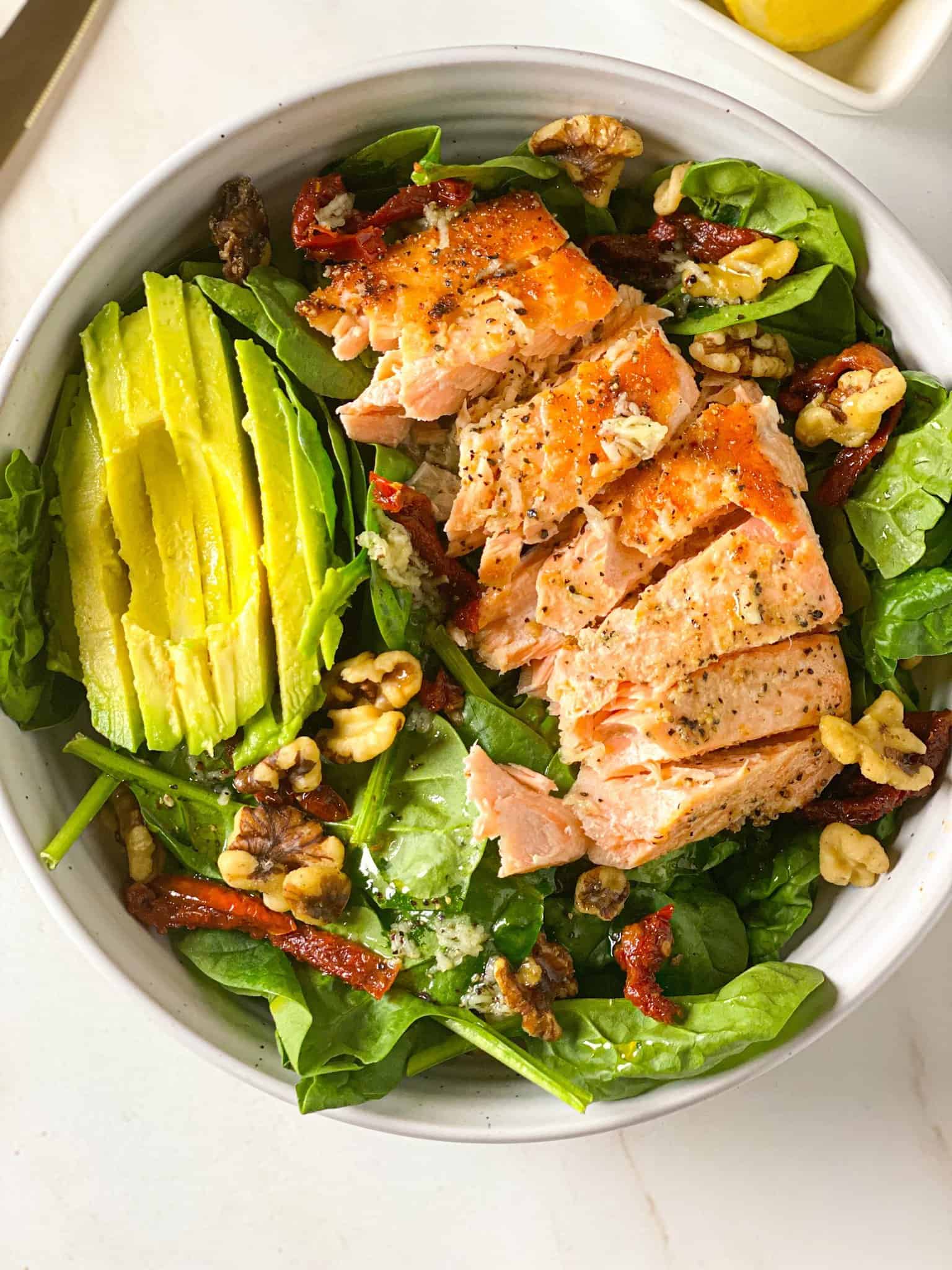 Salmon avocado salad in a white bowl.