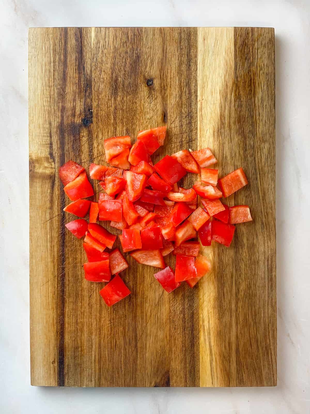 Chopped red bell peppers on a wooden cutting board.