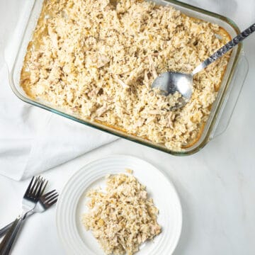 Dairy-free chicken and rice casserole served on a white plate with three crossed forks to its left and a glass pan of chicken and rice above it.