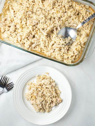 Dairy-free chicken and rice casserole served on a white plate with three crossed forks to its left and a glass pan of chicken and rice above it.