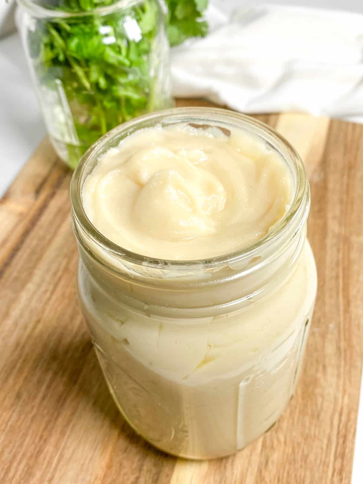 Dairy-free cream of chicken soup in a mason jar that is sitting on a wooden cutting board with bright green parsley behind it in a mason jar.