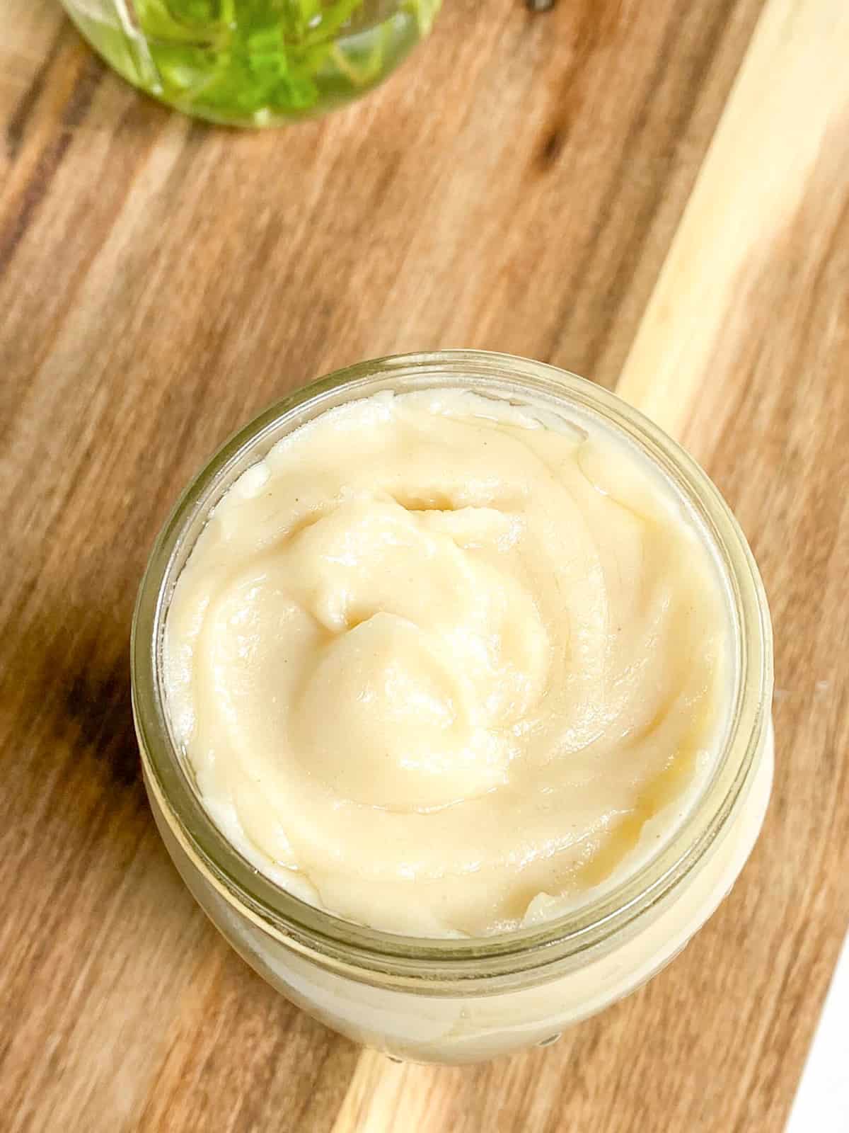 Overhead view of dairy-free cream of chicken soup in a mason jar on a wooden cutting board.