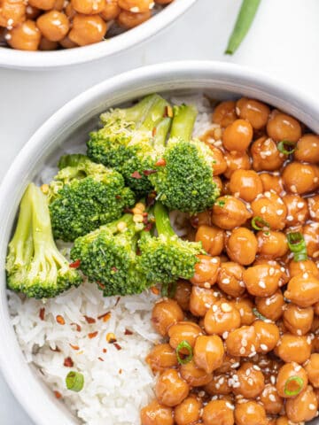 Sticky sesame chickpeas over white rice with broccoli, topped with green onions and red pepper flakes.