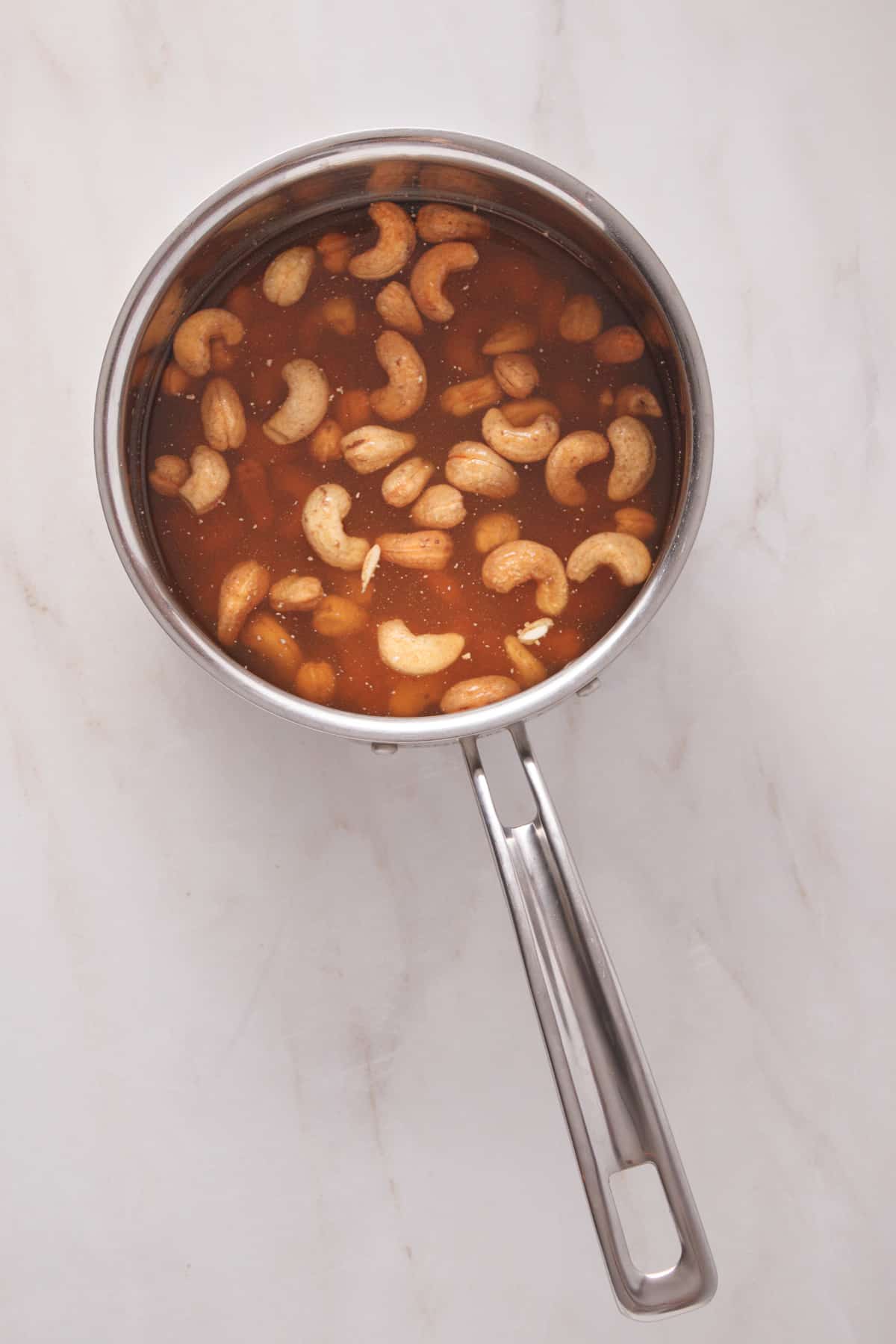 Cashews, vegetable broth and vodka in a stainless steel pot.