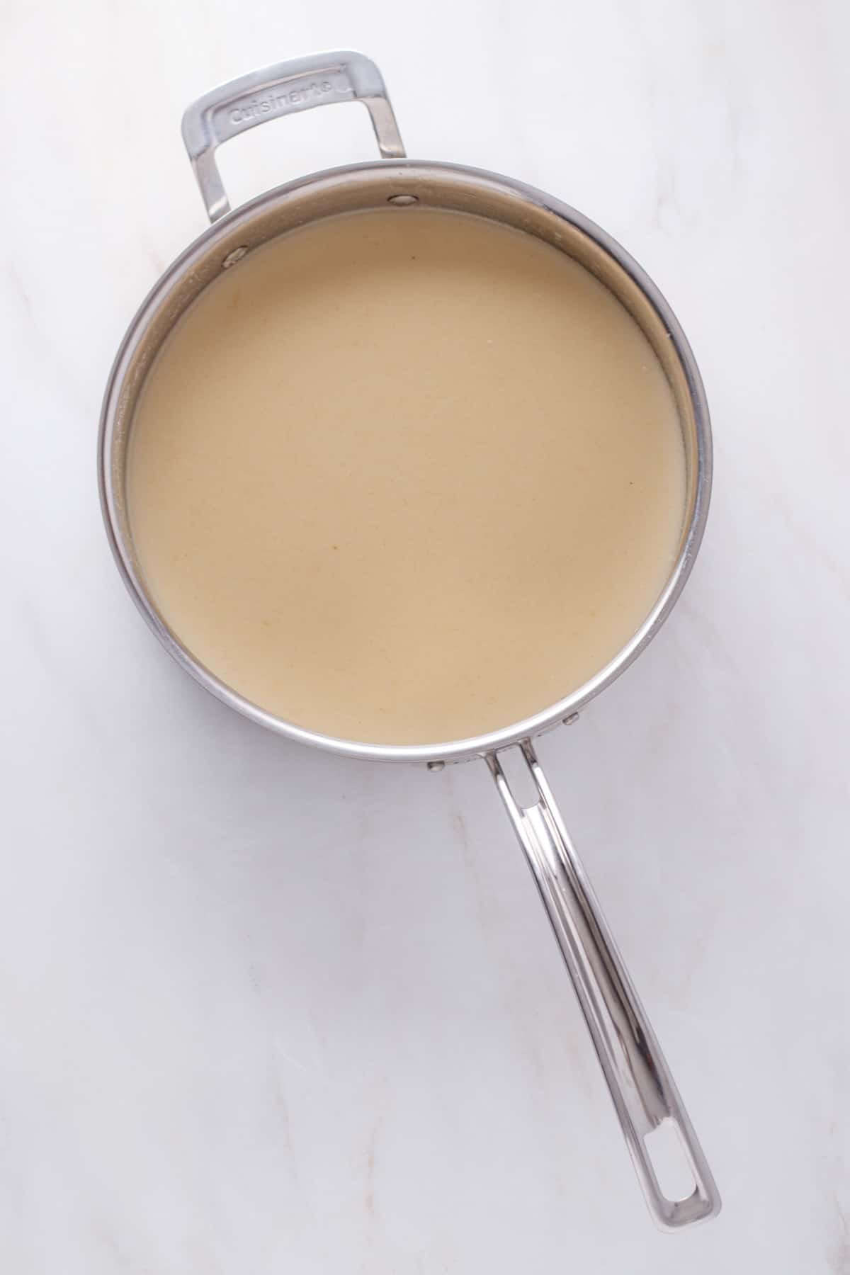 Roux with dairy-free milk and chicken broth in a pot.