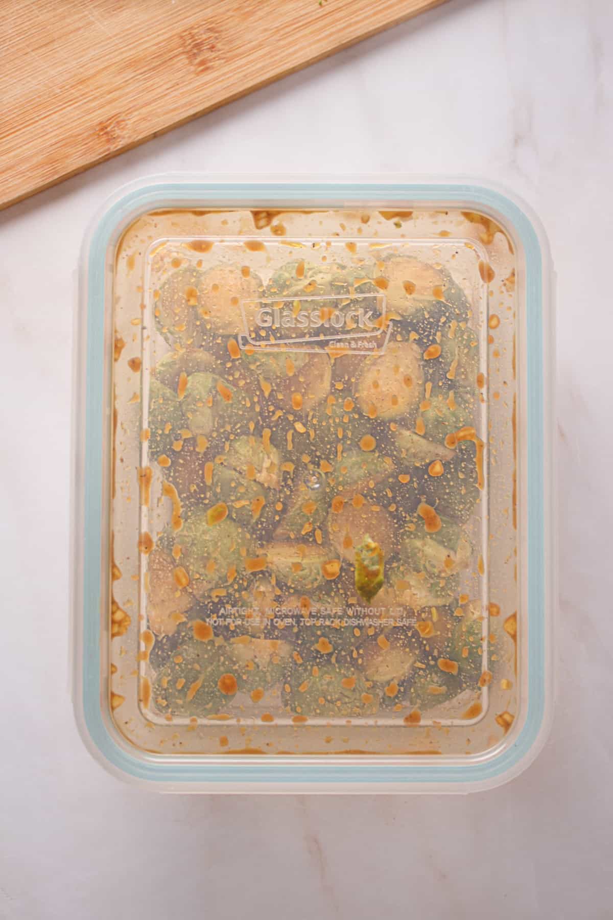 Brussel sprouts in a container with a lid after being shaken with the marinade.
