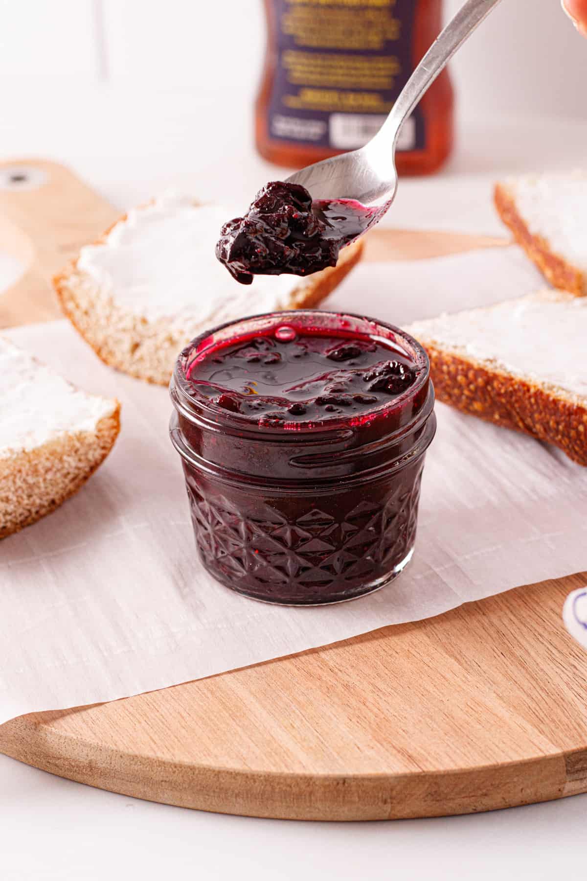 A spoonful of blueberry compote dipped out of a jar.