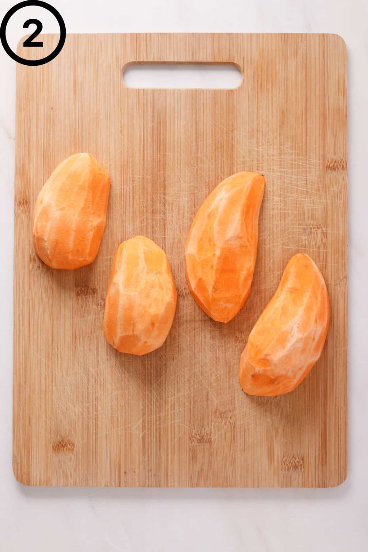 Peeled sweet potatoes sliced lengthwise.
