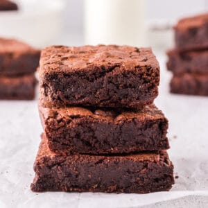 Brownies stacked on parchment paper.