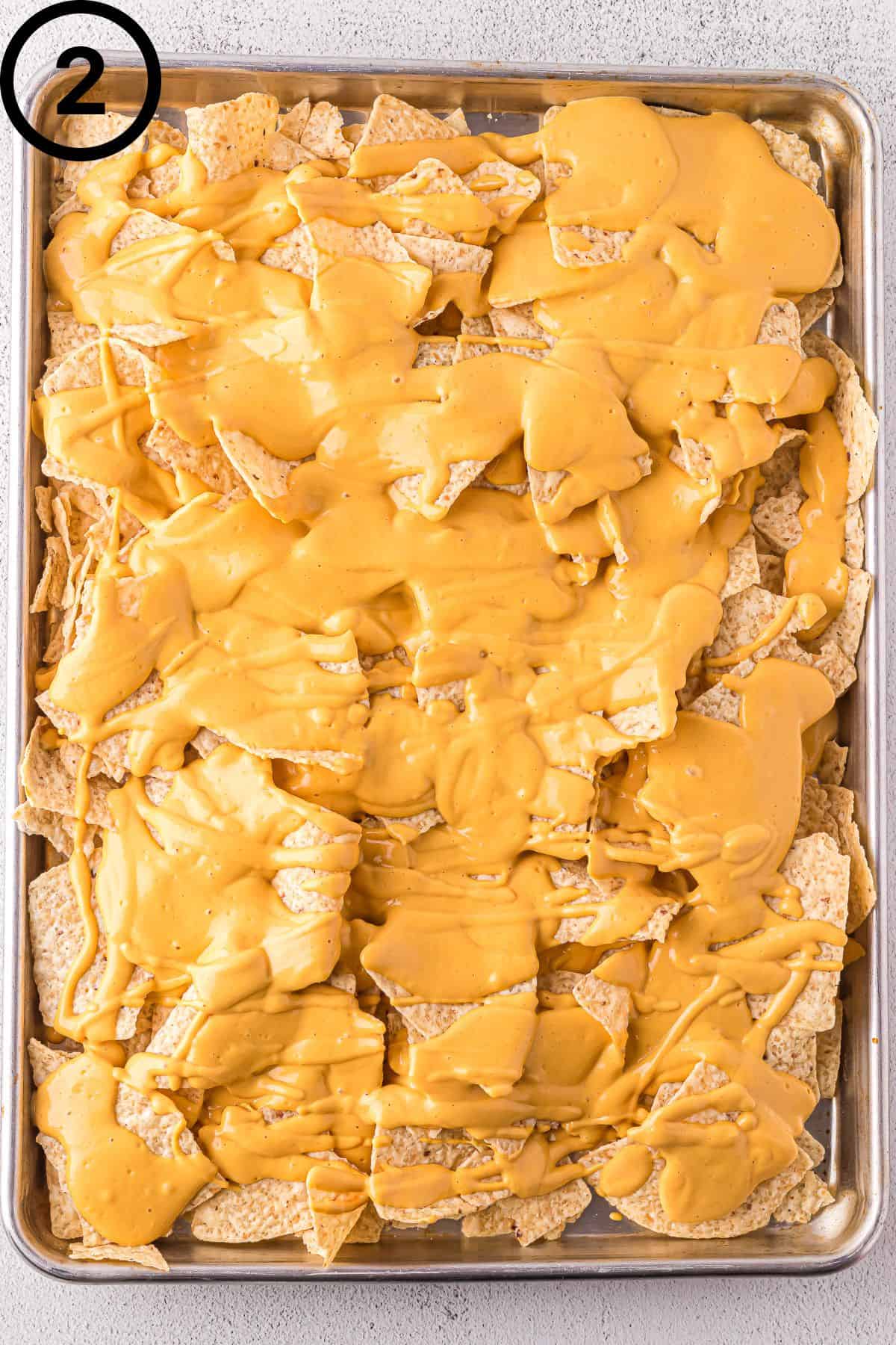 Tortilla chips with vegan cheese sauce on a baking sheet.