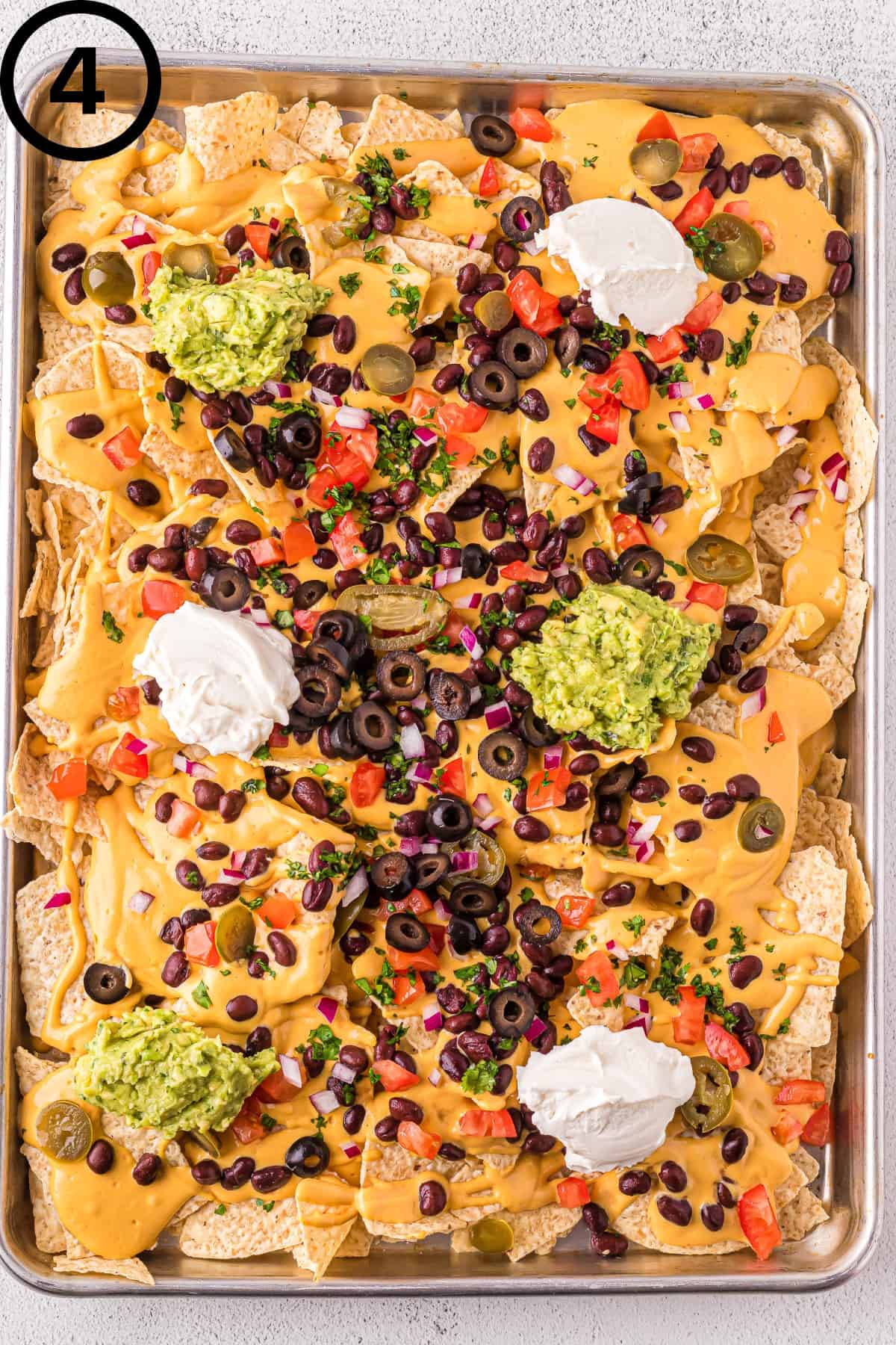 Fully assembled dairy-free nachos on a baking sheet.