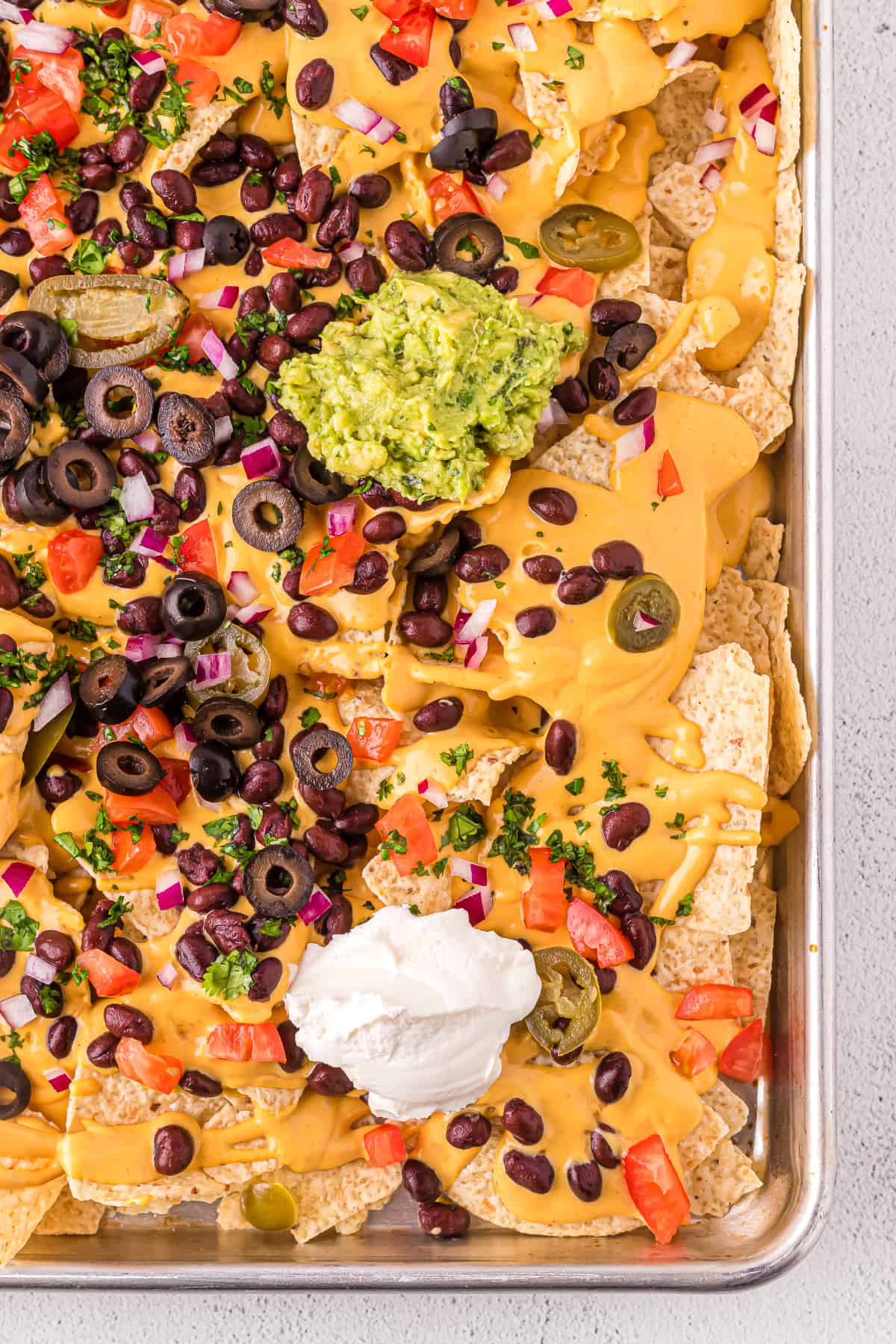 Dairy-free nachos with toppings on a baking sheet.
