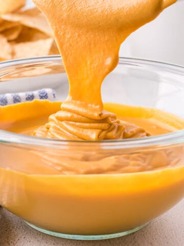 Vegan cheese sauce being poured into a glass bowl.