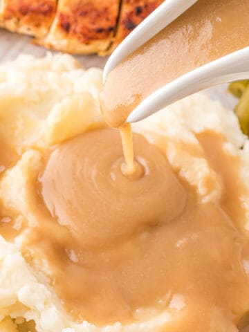 Pouring dairy-free brown gravy on to mashed potatoes.