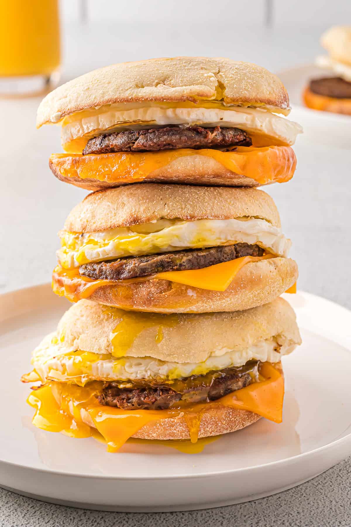 Three sausage breakfast sandwiches stacked on each other.