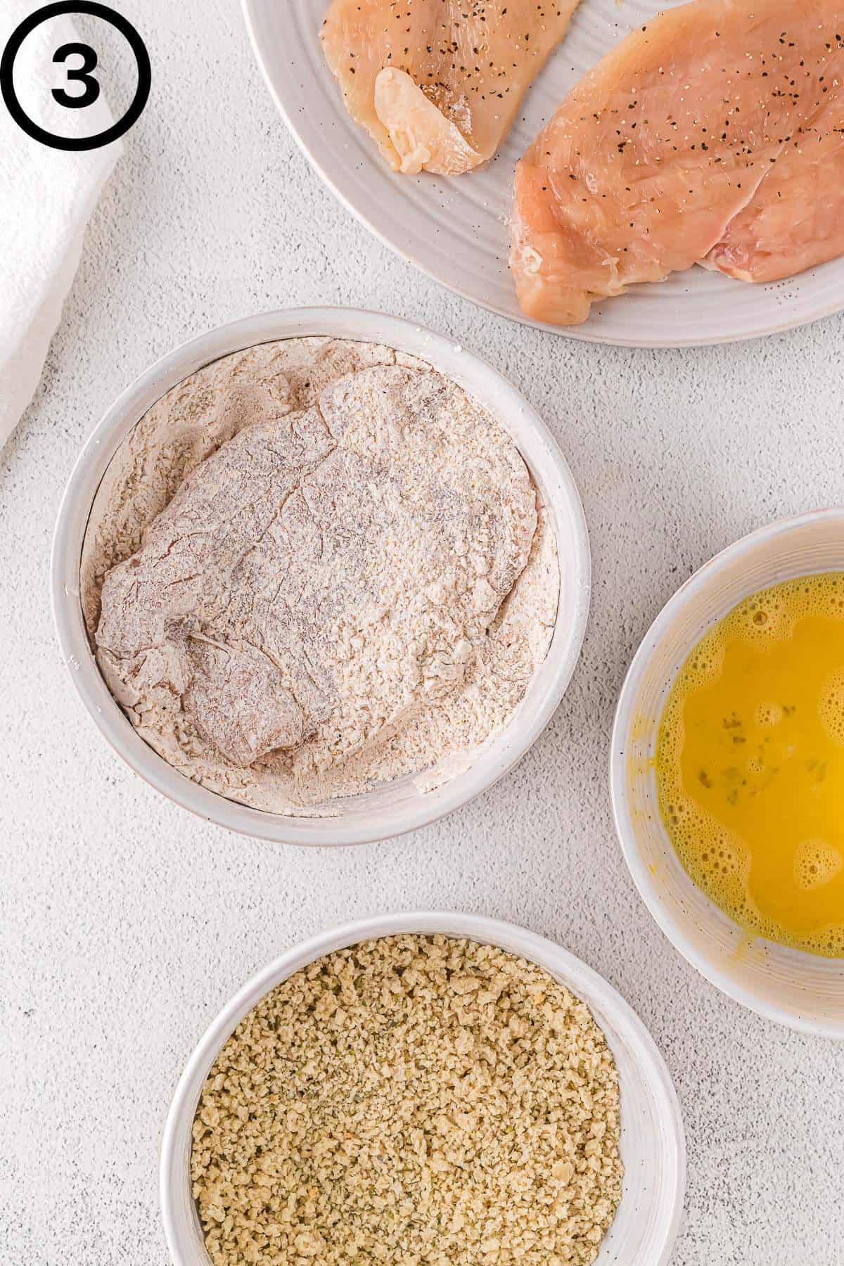 Chicken breast in the seasoned flour bowl.