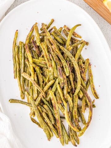 Roasted green beans on a white serving dish.