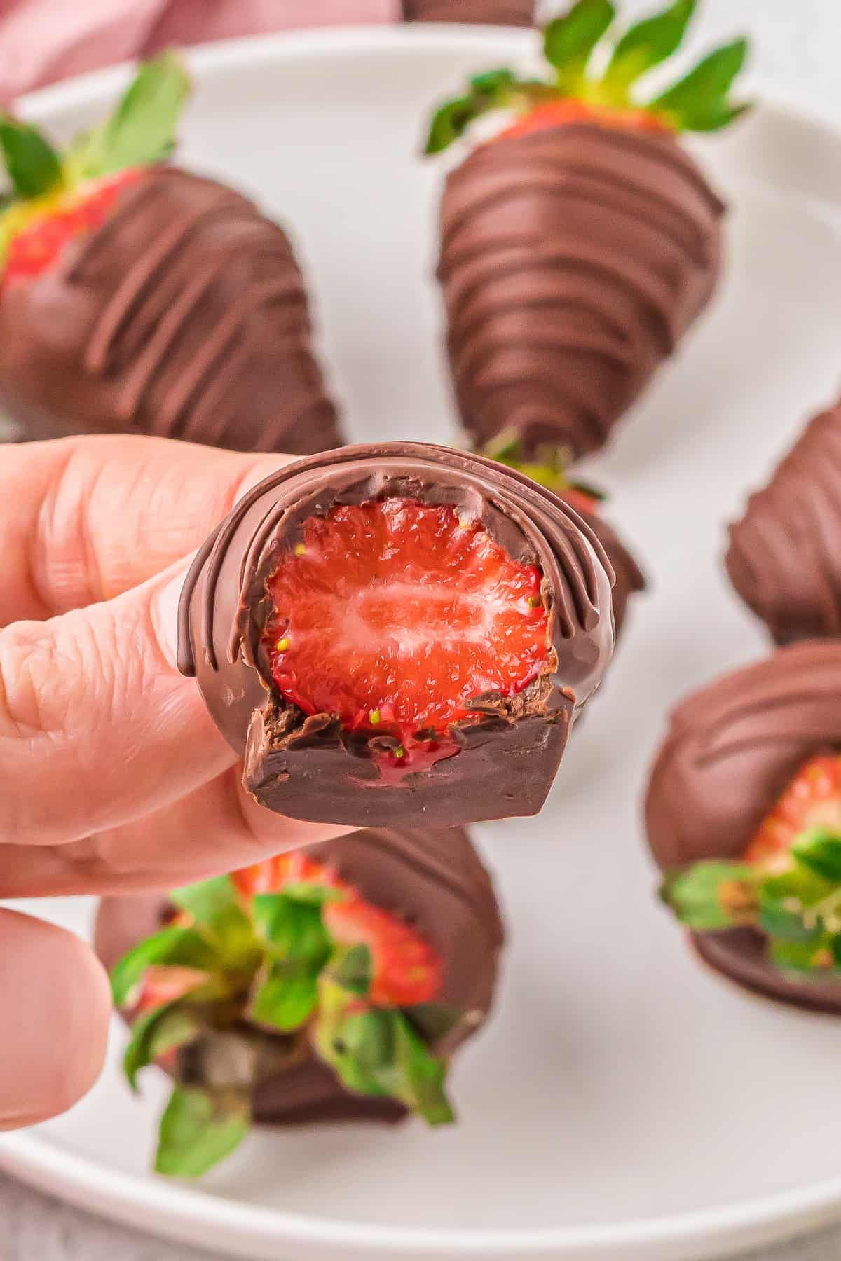 Vegan chocolate covered strawberry with a bite removed.