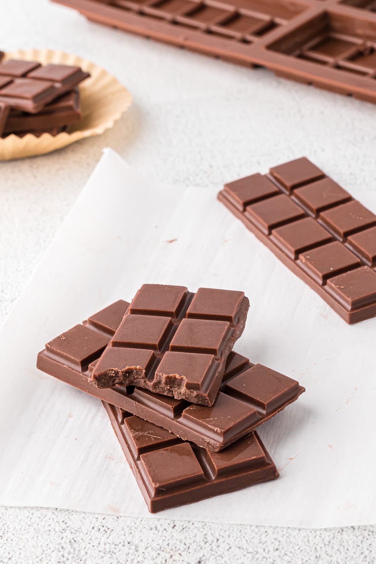 Dairy-free chocolate bars stacked on white parchment paper.